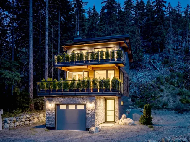 Modern home featuring stone siding, a balcony, and an attached garage