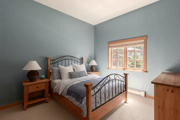 Bedroom featuring a window with natural wood trim, light blue wall color, baseboard heating, and light-toned carpeting