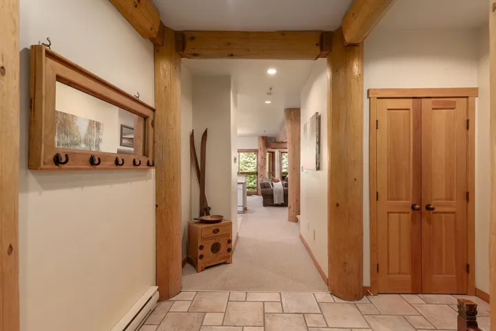 Foyer with natural wood structural beams and a tiled entry