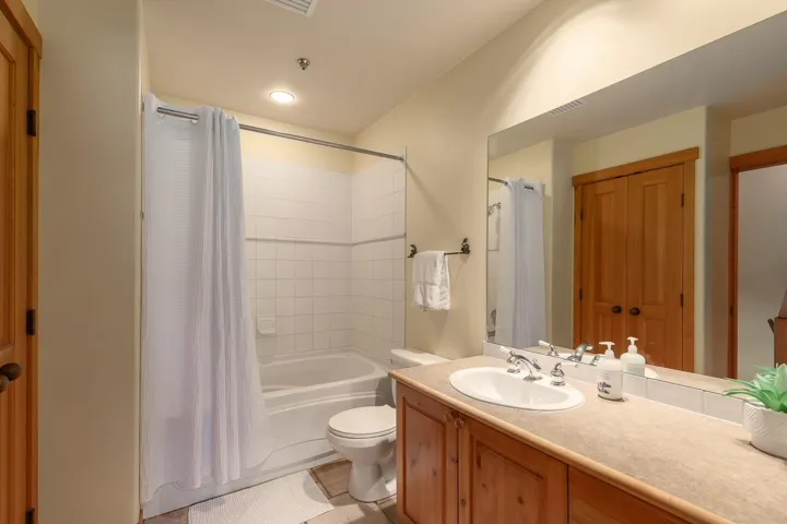 Full bathroom featuring a single vanity with an integrated sink, a light-toned countertop, and wood-finish cabinetry