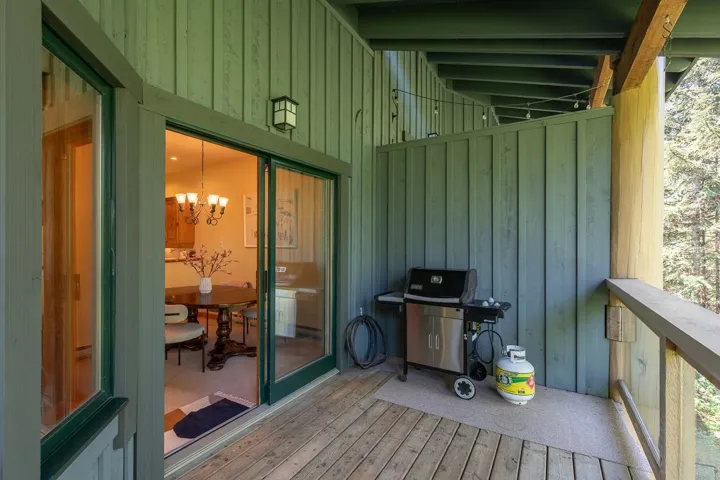 Wood-plank balcony with board and batten siding, outdoor lighting fixture, and sliding glass doors