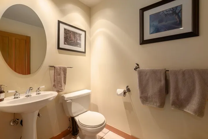 Pedestal sink with chrome fixtures, oval wall mirror, and neutral wall paint