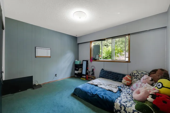 Bedroom featuring a textured ceiling, carpet, and wood walls