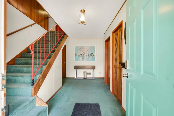 Foyer with dark colored carpet and stairway