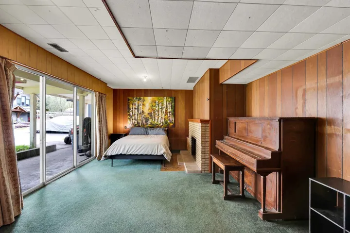 Bedroom featuring wood walls, carpet floors, and access to outside