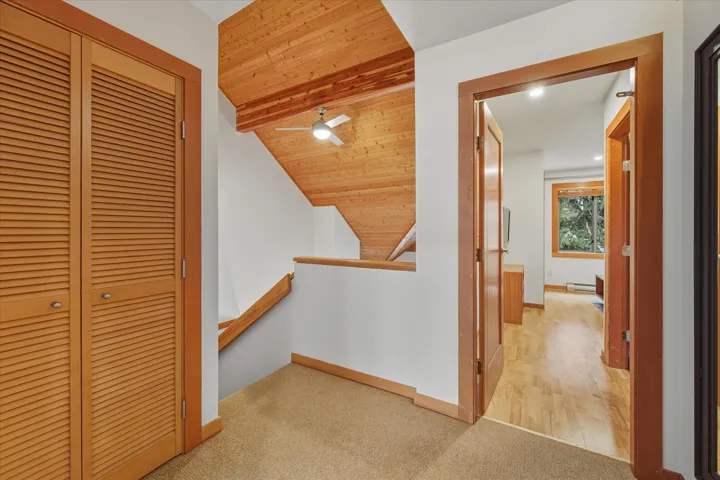 Corridor with light carpet, an upstairs landing, wood ceiling, recessed lighting, and baseboard heating