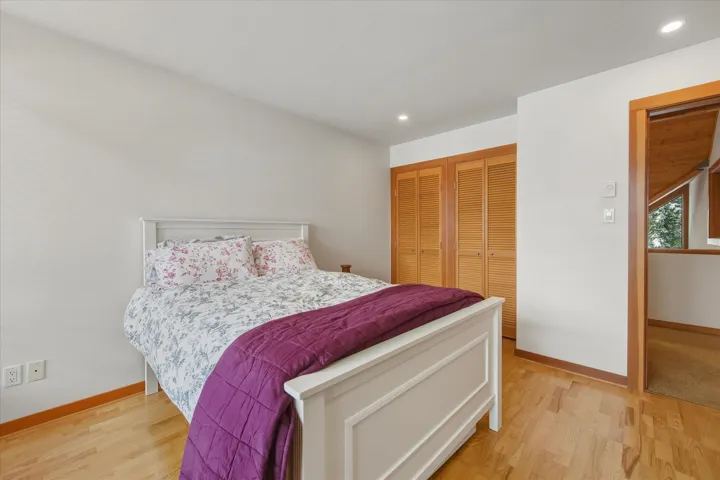 Bedroom featuring two closets, recessed lighting, and light wood-style flooring
