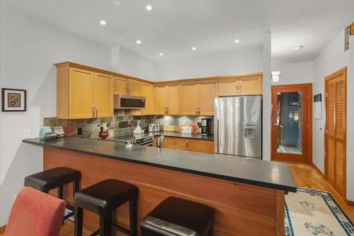 Kitchen with appliances with stainless steel finishes, tasteful backsplash, recessed lighting, a breakfast bar, and a peninsula
