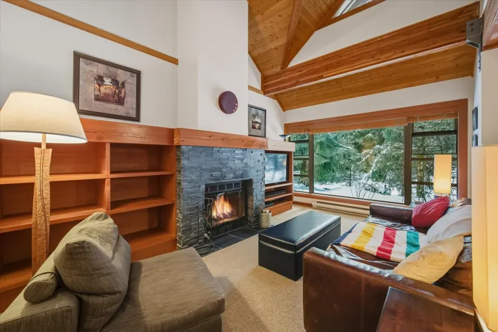 Living area with a fireplace, high vaulted ceiling, wood ceiling, and a baseboard heating unit