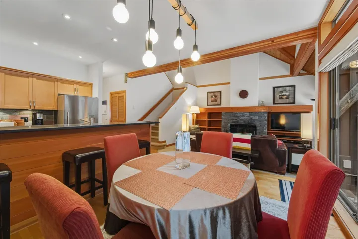 Dining area featuring a fireplace, light wood-style flooring, stairs, vaulted ceiling, and recessed lighting