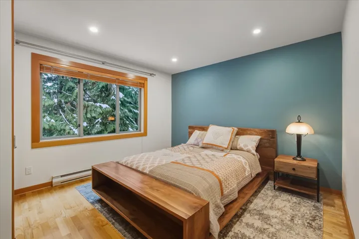 Bedroom with a baseboard heating unit, light wood-style flooring, and recessed lighting