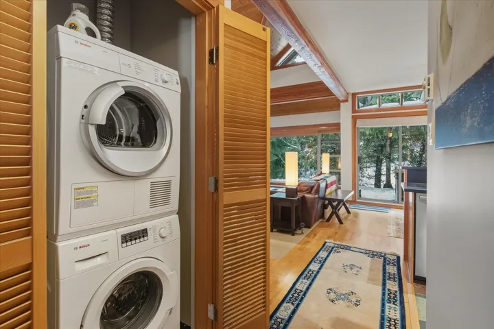 Laundry room featuring stacked washer / drying machine and light wood-style flooring