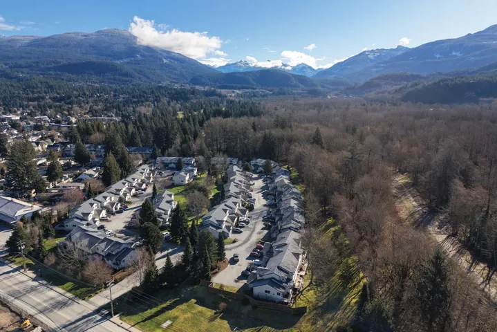 Aerial perspective of suburban area with a mountainous background and a heavily wooded area
