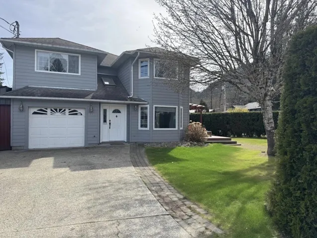 View of front facade featuring a garage, a front yard, driveway, and a shingled roof