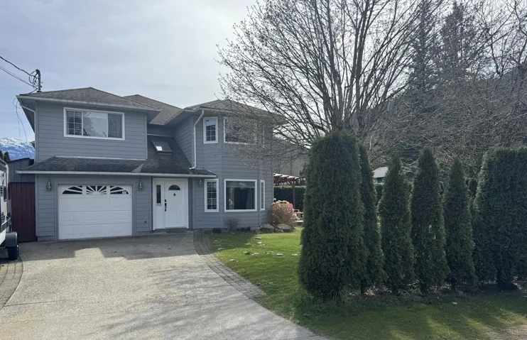 View of front of house with an attached garage, roof with shingles, driveway, and a front lawn