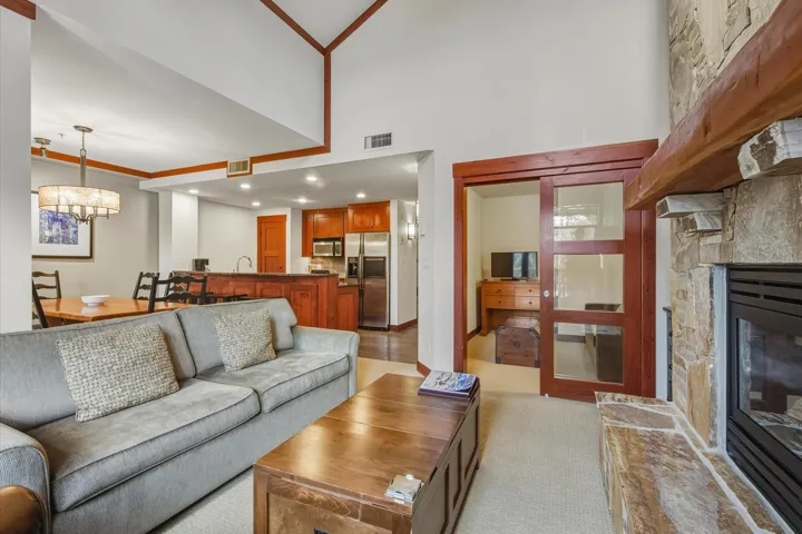 Living area featuring a fireplace, recessed lighting, light carpet, a chandelier, and a towering ceiling