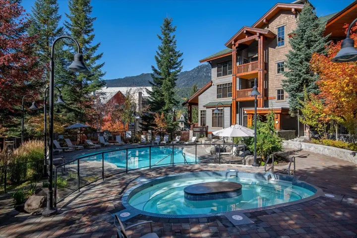 Community pool with a patio, a hot tub, a mountain view, and a balcony