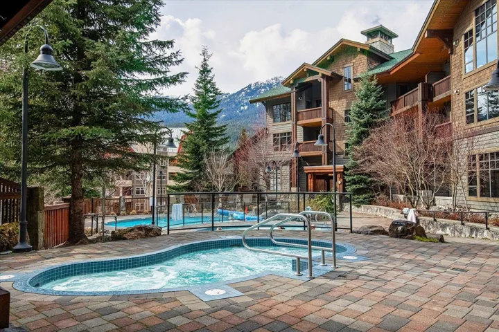 Community pool featuring a patio area, a mountain view, and a hot tub