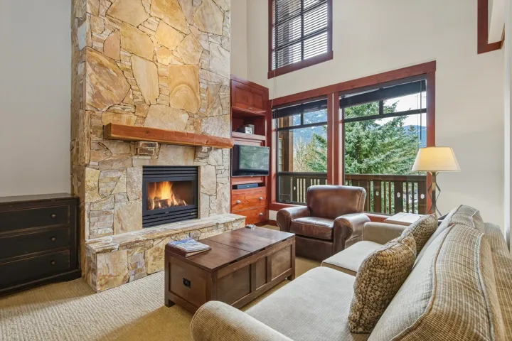 Living room featuring a high ceiling, a fireplace, and carpet floors
