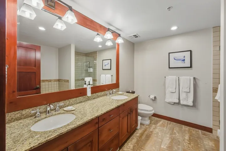 Full bathroom with double vanity, tiled shower, and recessed lighting