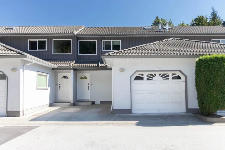 View of front of home with a tiled roof, a garage, stucco siding, and driveway