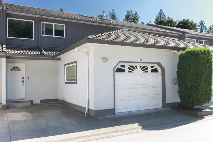 View of front of home with a tiled roof, an attached garage, and stucco siding