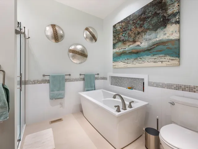 Bathroom featuring a freestanding tub, tile walls, wainscoting, and a stall shower