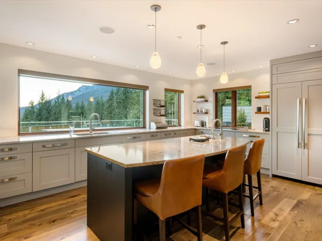 Kitchen with hanging light fixtures, light stone countertops, white cabinets, a kitchen breakfast bar, and light wood finished floors