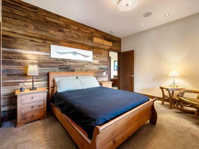 Bedroom with wooden walls, light colored carpet, and an accent wall