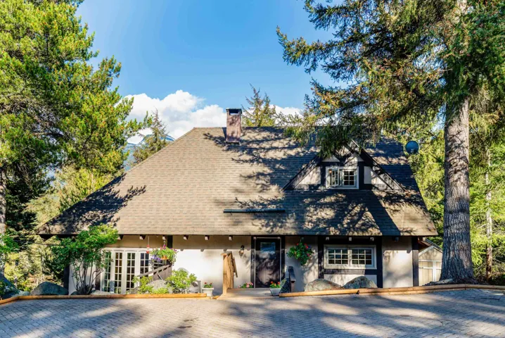 Tudor-style architecture featuring a pitched roof, dormer windows, and a paved driveway