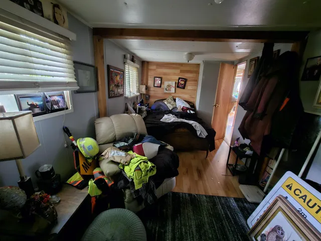 Bedroom with wood walls, wood finished floors, and beam ceiling