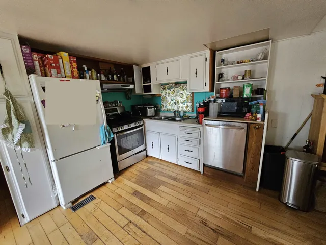 Kitchen with open shelves, white cabinetry, and stainless steel appliances
