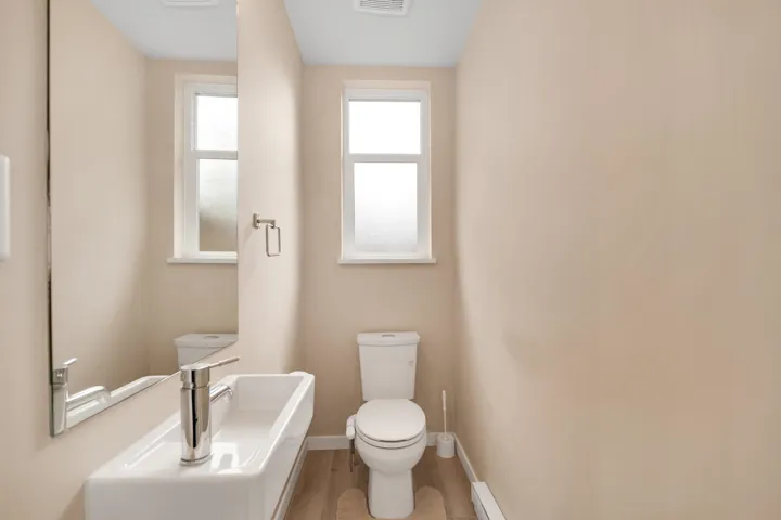 Half bathroom with wood finished floors and a baseboard heating unit