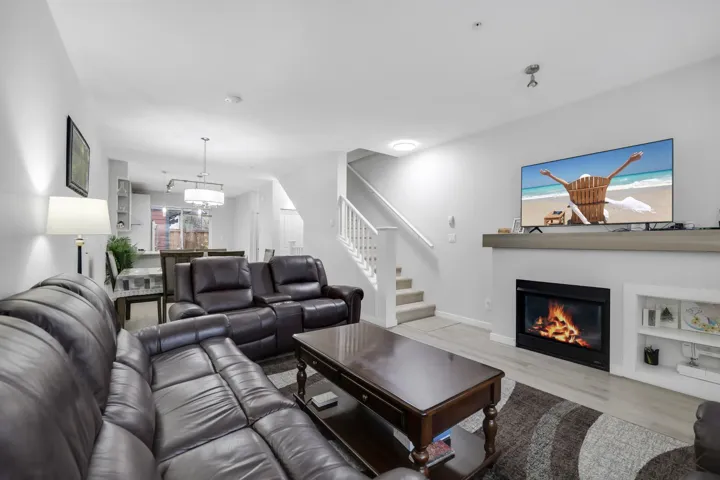 Living room featuring a glass covered fireplace, stairway, and wood finished floors