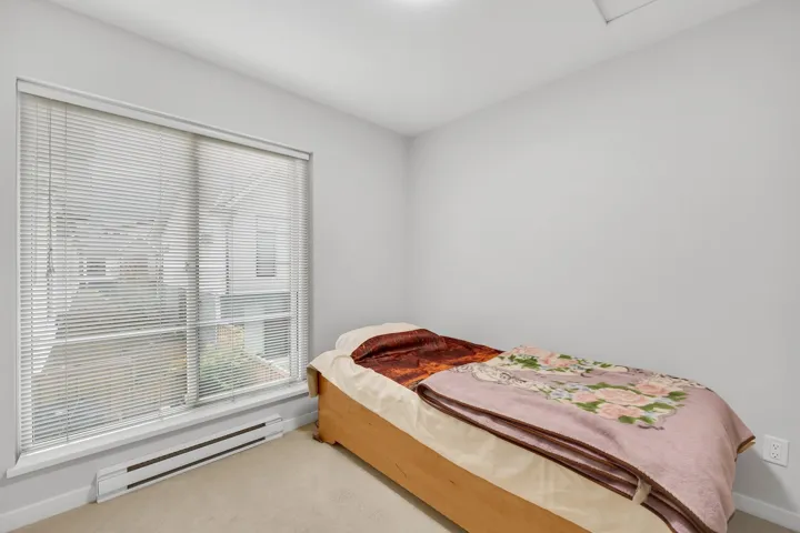 Carpeted bedroom featuring a baseboard heating unit and baseboards