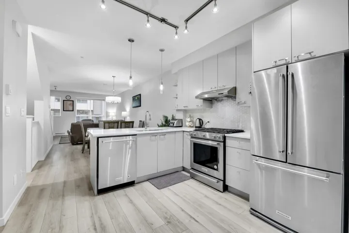 Kitchen with stainless steel appliances, a peninsula, open floor plan, hanging light fixtures, and decorative backsplash