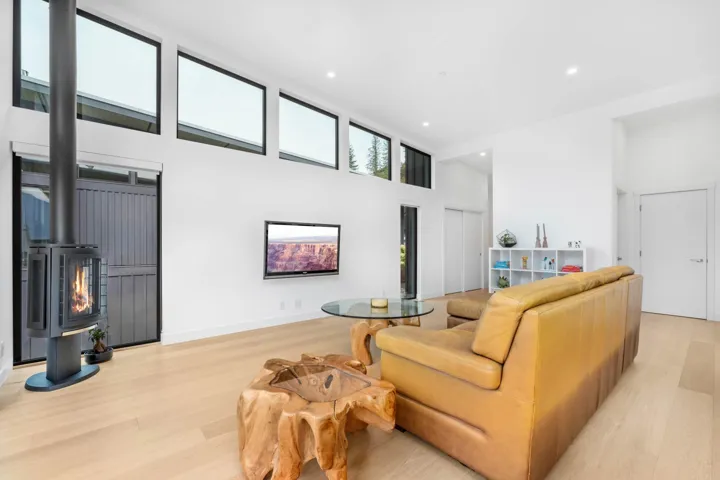Living area featuring light wood-style floors, a wood stove, a high ceiling, and recessed lighting