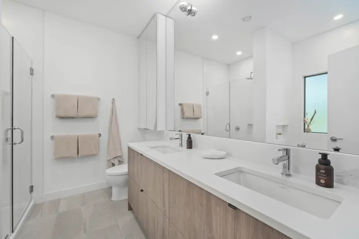 Bathroom featuring a stall shower, double vanity, light tile patterned flooring, and recessed lighting