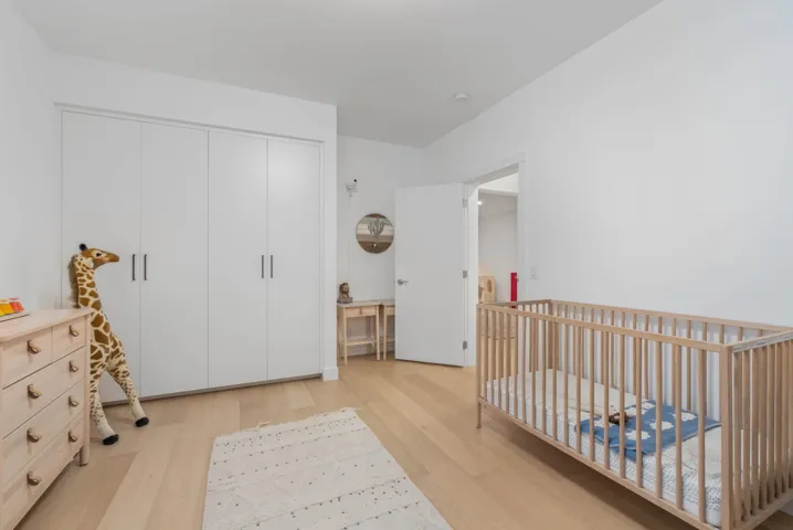 Bedroom featuring light wood-style flooring, a nursery area, and a closet