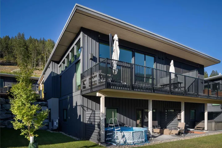 Rear view of property with a patio area, board and batten siding, an outdoor pool, and a balcony