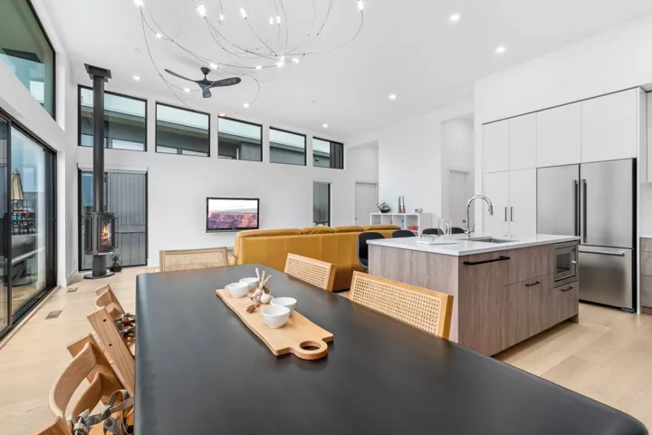 Dining room featuring light wood-style flooring, a wood stove, recessed lighting, a towering ceiling, and healthy amount of natural light