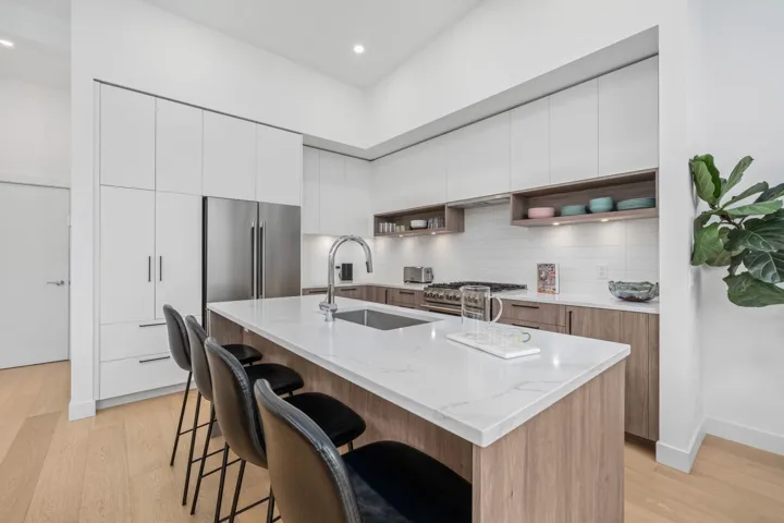 Kitchen featuring modern cabinets, a kitchen breakfast bar, decorative backsplash, white cabinetry, and recessed lighting