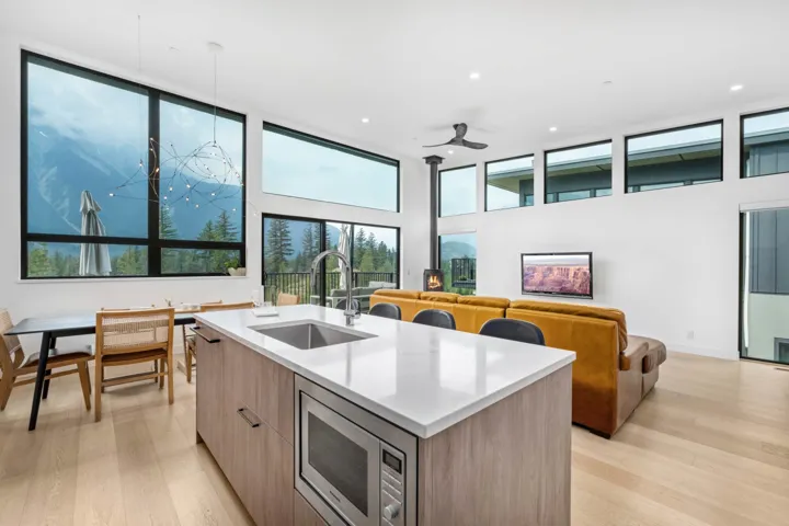 Kitchen with modern cabinets, light stone countertops, stainless steel microwave, light wood finished floors, and open floor plan