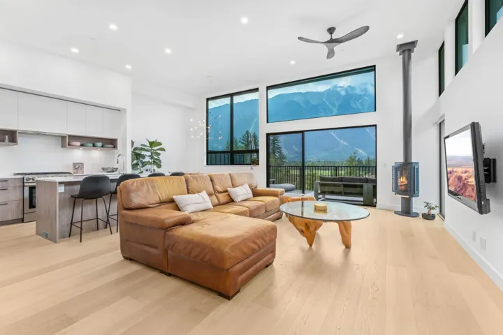 Living area with recessed lighting, a wood stove, a ceiling fan, light wood-style flooring, and a towering ceiling