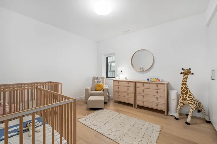 Bedroom with a crib and light wood-type flooring