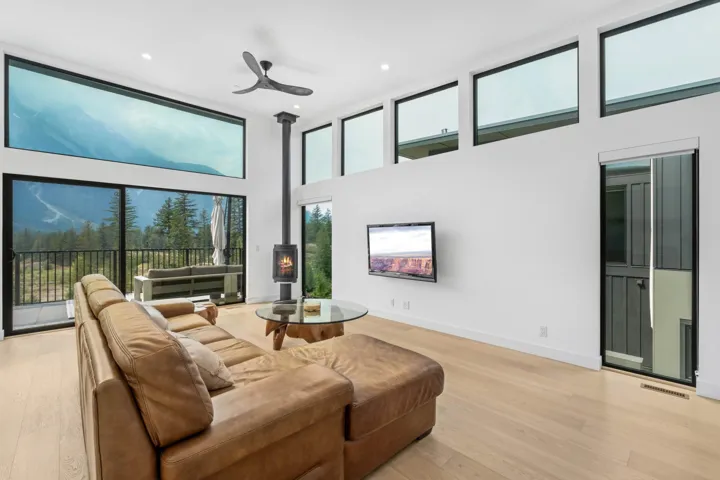 Living room featuring a wood stove, healthy amount of natural light, a towering ceiling, light wood-type flooring, and recessed lighting