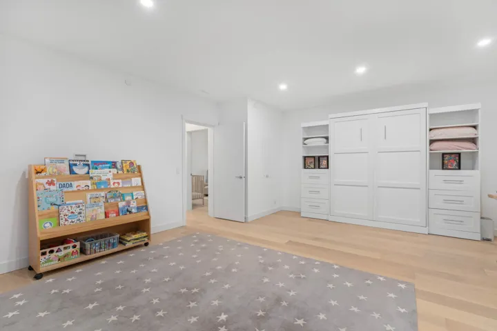 Recreation room with light wood-style flooring and recessed lighting