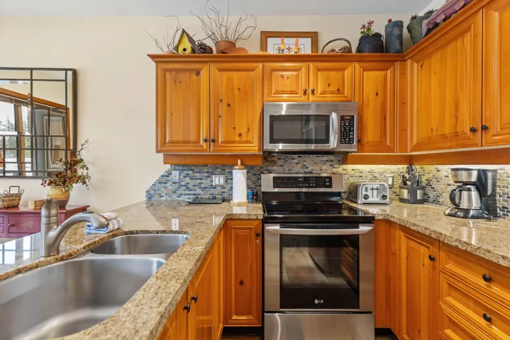 Kitchen featuring brown cabinetry, a sink, tasteful backsplash, and appliances with stainless steel finishes