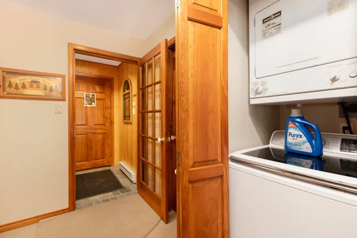 Washroom featuring a baseboard radiator, stacked washer / dryer, and laundry area