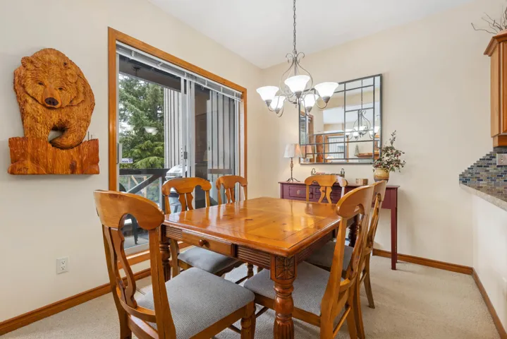 Dining space featuring baseboards, light colored carpet, and a chandelier